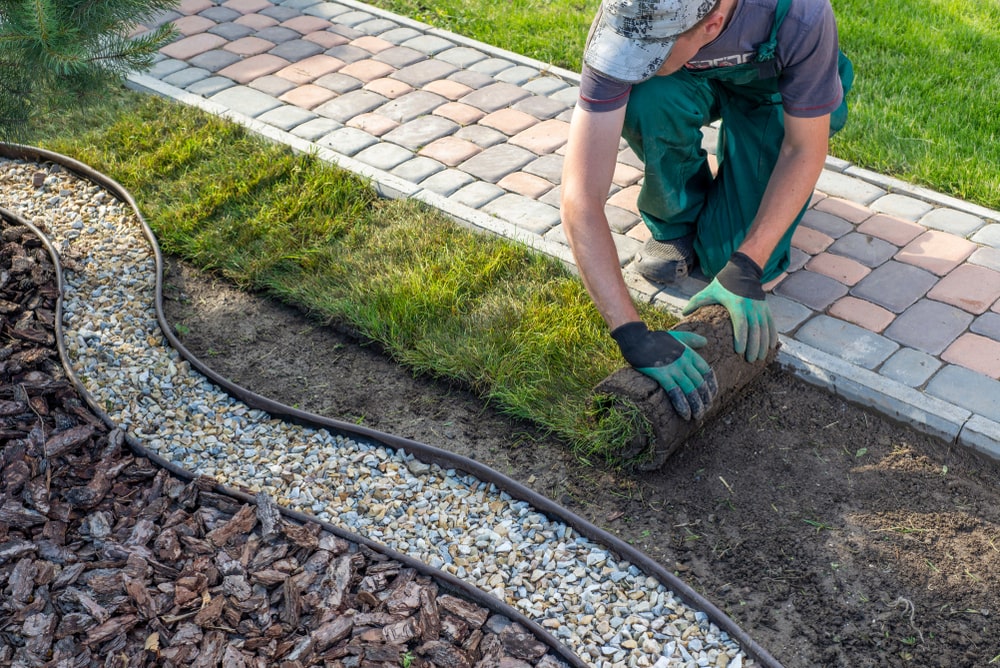 A professional putting in an artificial grass - Why Professional Landscaping is a Good Investment for Your Property