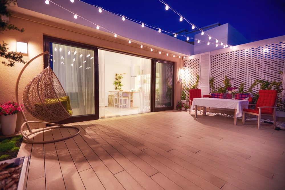 rooftop patio area with hanging swing chair and string lights at night - Factors to Consider When Planning an Outdoor Living Space