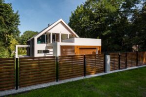 Large white house with wooden accents on garage and wooden-style fence, showcasing the aesthetic and functional benefits of choosing the right fence in New Orleans.